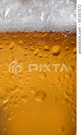 Liquid drops on a foamy beer glass close-up Liquid drops on a foamy beer glass close-up 95387872