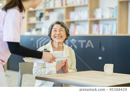 Senior woman long-term care image meal serving 95388429