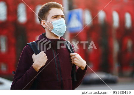 Portrait of men in protective sterile medical mask on her face on the street city. pandemic in quarantine city. Portrait of men in protective sterile medical mask on her face on the street city. pandemic in quarantine city. 95388459