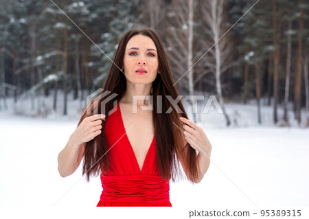 beautiful brunette girl in a thin red dress and barefoot in the winter forest beautiful brunette girl in a thin red dress and barefoot in the winter forest 95389315