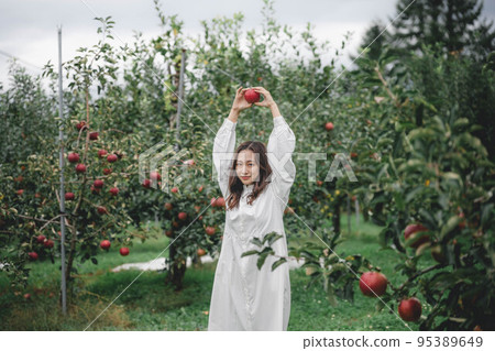 A woman in a white dress with an apple A woman in a white dress with an apple 95389649