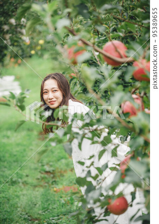 A woman in a white dress with an apple A woman in a white dress with an apple 95389655
