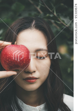 A woman in a white dress with an apple A woman in a white dress with an apple 95389674