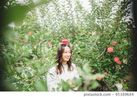 A woman in a white dress with an apple 95389684