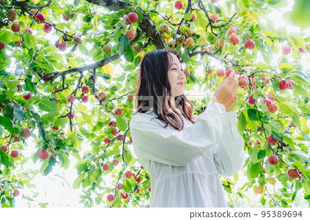 一個穿著白色連衣裙的女人拿著一個蘋果 一個穿著白色連衣裙的女人拿著一個蘋果 95389694