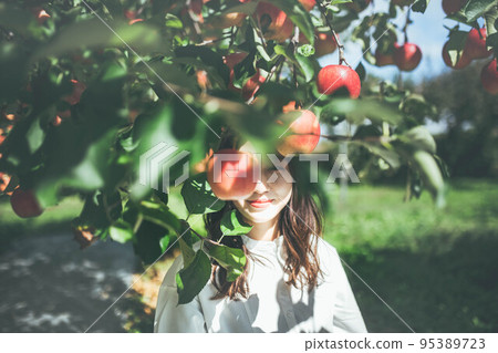 A woman in a white dress with an apple A woman in a white dress with an apple 95389723