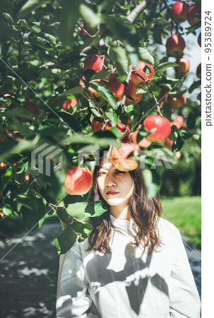 A woman in a white dress with an apple A woman in a white dress with an apple 95389724