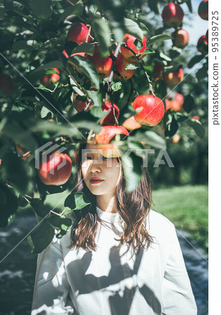 A woman in a white dress with an apple 95389725