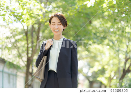 一個穿著西裝的女人在綠色中行走 95389805