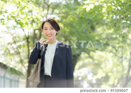 一個穿著西裝的女人在綠色中行走 一個穿著西裝的女人在綠色中行走 95389807