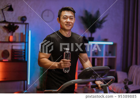 Attractive young sports asian man holding out bottle with fresh water, working out, running Attractive young sports asian man holding out bottle with fresh water, working out, running 95389885