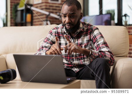 Young freelancer talking on online videoconference, attending remote internet meeting with colleagues. Using videocall conference on webcam with laptop, chatting on teleconference call. 95389971