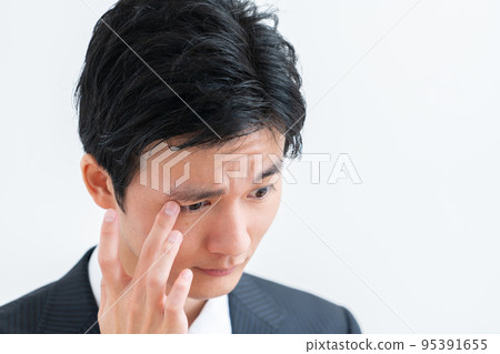 揉眼睛的年輕商人 95391655