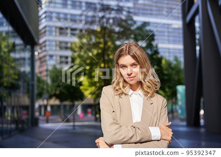 Portrait of confident ceo manager, young businesswoman in suit, looking determined and self-assured, posing on street on sunny day Portrait of confident ceo manager, young businesswoman in suit, looking determined and self-assured, posing on street on sunny day 95392347