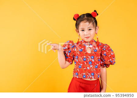 Happy Asian Chinese little girl wear red cheongsam qipao pointing finger to space 95394950
