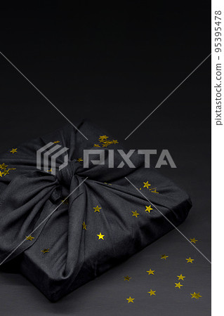 Black friday gift box wrapped in fabric with golden confetti. Traditional Japanese gift wrapping furoshiki style. Eco friendly holiday concept. Black friday gift box wrapped in fabric with golden confetti. Traditional Japanese gift wrapping furoshiki style. Eco friendly holiday concept. 95395478