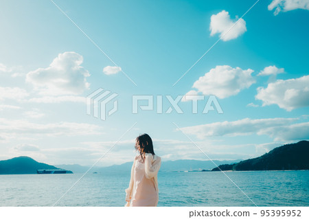 Photo of a woman standing by the beach Photo of a woman standing by the beach 95395952