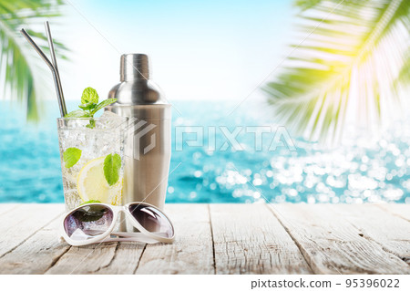Mojito cocktail on wooden table in front of sunny sea Mojito cocktail on wooden table in front of sunny sea 95396022