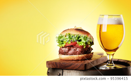 Draft beer glass and hamburger on wooden barrel Draft beer glass and hamburger on wooden barrel 95396415