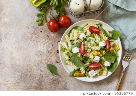 Salad with gluten free pasta, spinach, tomatoes, beans and feta cheese on a stone table. Italian food. Healthy food, vegetarian appetizer. View from above. Salad with gluten free pasta, spinach, tomatoes, beans and feta cheese on a stone table. Italian food. Healthy food, vegetarian appetizer. View from above. 95396779