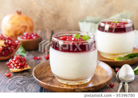 Winter delicious italian dessert panna cotta with pomegranate jelly and mint, homemade cuisine on a wooden background. Winter delicious italian dessert panna cotta with pomegranate jelly and mint, homemade cuisine on a wooden background. 95396780