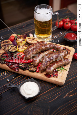 Grilled sausages and vegetables on wooden cutting board at domestic kitchen Grilled sausages and vegetables on wooden cutting board at domestic kitchen 95396981