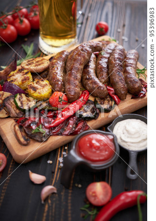 Grilled sausages and vegetables on wooden cutting board at domestic kitchen Grilled sausages and vegetables on wooden cutting board at domestic kitchen 95396983