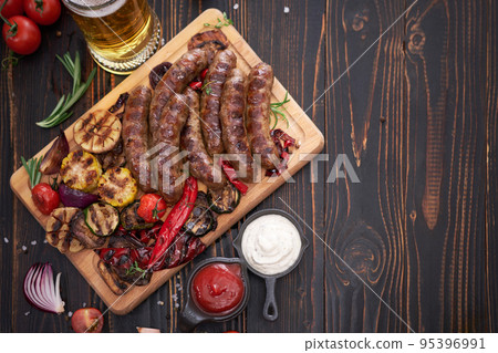 Grilled sausages and vegetables on wooden cutting board at domestic kitchen Grilled sausages and vegetables on wooden cutting board at domestic kitchen 95396991