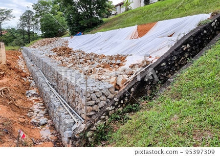 Series of slope retention construction design with rocks and mesh to manage landslide 95397309