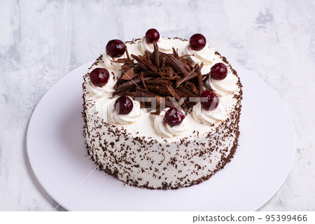A closeup shot of white cream on Black Forest gateau cake with cherries on white marble surface A closeup shot of white cream on Black Forest gateau cake with cherries on white marble surface 95399466