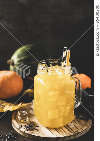 Halloween pumpkin iced cocktails in glass jars on a stone table. Party cocktails. Copy space. Toned image. Halloween pumpkin iced cocktails in glass jars on a stone table. Party cocktails. Copy space. Toned image. 95400200