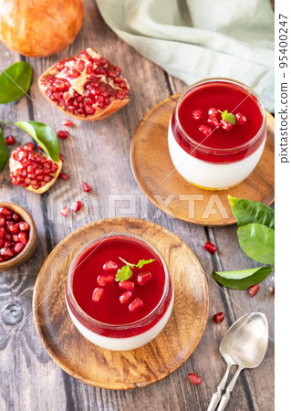 Winter delicious italian dessert panna cotta with pomegranate jelly and mint, homemade cuisine on a wooden background. 95400247