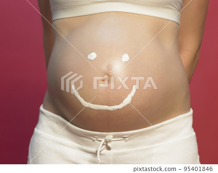 Pregnant woman with smiley face on stomach Pregnant woman with smiley face on stomach 95401846