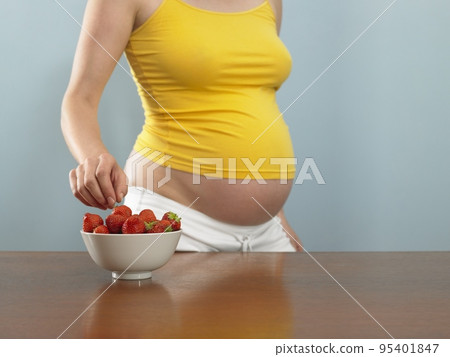 Pregnant woman choosing a strawberry Pregnant woman choosing a strawberry 95401847
