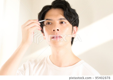 Young man doing self-makeup Men's beauty image Young man doing self-makeup Men's beauty image 95402878