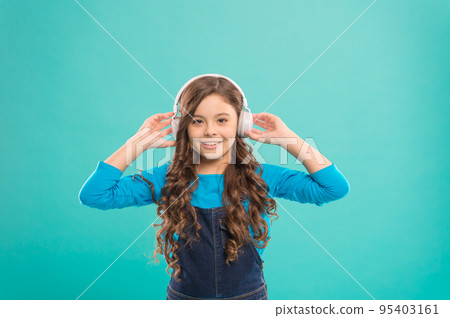 Sound of the childhood. Adorable little girl listening to sound track on blue background. Cute small child wearing headphones playing electronic sound. Relaxing with melodious sound 95403161