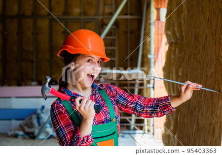 Childrens creativity. kid wear helmet on construction site. teen girl builder with building tool hammer. child on repairing work. concept of renovation in workshop. busy professional carpenter Childrens creativity. kid wear helmet on construction site. teen girl builder with building tool hammer. child on repairing work. concept of renovation in workshop. busy professional carpenter 95403363