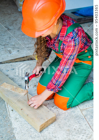 working with wood in a garage. happy childhood. hardworking child hammering nail. teenage girl with hammer. little girl working with wood. kid in carpentry working with wood in a garage. happy childhood. hardworking child hammering nail. teenage girl with hammer. little girl working with wood. kid in carpentry 95403365
