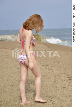 Young woman wearing a bikini swimsuit on the beach Young woman wearing a bikini swimsuit on the beach 95403688