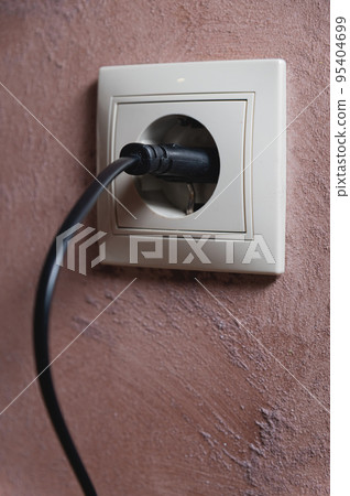 White electrical outlet on the wall with a black wire inserted. close-up, home decor 95404699
