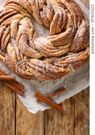 Estonian Kringle Cinnamon Braid Bread with powdered sugar closeup on the paper. Vertical top view Estonian Kringle Cinnamon Braid Bread with powdered sugar closeup on the paper. Vertical top view 95405023