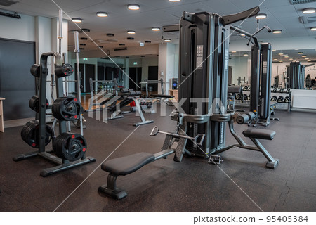 Modern light gym. Sports equipment in gym. Barbells of different weight on rack. 95405384