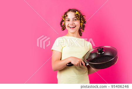 Shop home utensils. Kitchen accessories. Culinary and house duties. Stereotype housewife style. Small girl with curlers in hair. Girl hold Frying Pan. Little kid hold pan cooking meal. Pin up style 95406246