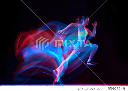 Professional female athlete, runner in motion over dark background in mixed neon light. Art, beauty, sport, cyberpunk concept Professional female athlete, runner in motion over dark background in mixed neon light. Art, beauty, sport, cyberpunk concept 95407249