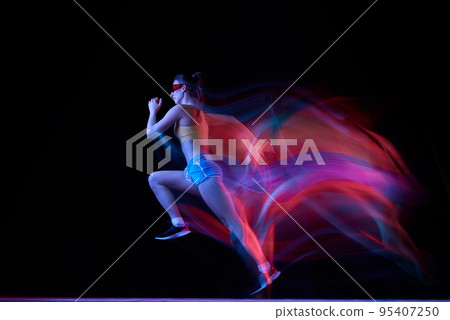 Professional female athlete, runner in motion over dark background in mixed neon light. Art, beauty, sport, cyberpunk concept Professional female athlete, runner in motion over dark background in mixed neon light. Art, beauty, sport, cyberpunk concept 95407250