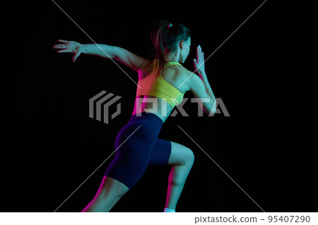 Run away. Professional female athlete running isolated on dark background in neon light. Healthy lifestyle, skills, sport, fitness, speed and energy concept. 95407290