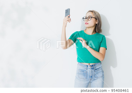 A woman in a green T-shirt with a smartphone 95408461