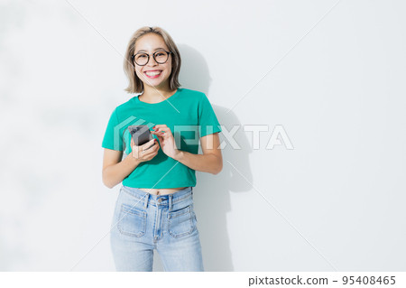 A woman in a green T-shirt with a smartphone 95408465