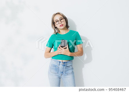A woman in a green T-shirt with a smartphone 95408467