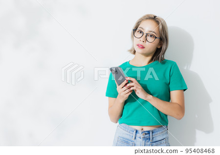 A woman in a green T-shirt with a smartphone 95408468